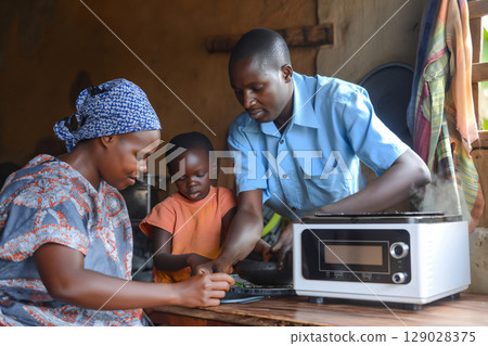 African family is happily preparing a meal together using a modern kitchen appliance African family is happily preparing a meal together using a modern kitchen appliance 129028375