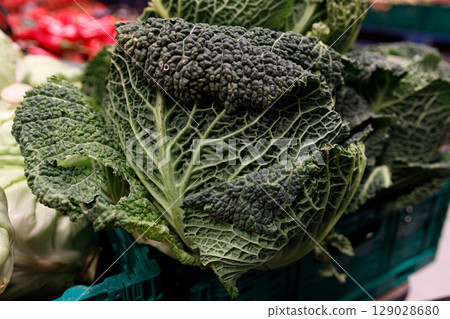 Fresh Savoy Cabbage Displayed in a Market: A Vibrant Showcase of Green Vegetables with Intricate Leaf Patterns and a Fresh, Nutrient-Dense Appearance in a Vibrant Setting 129028680