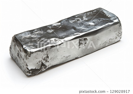 Rough and polished steel ingot lying on a white background, showcasing its metallic texture 129028917