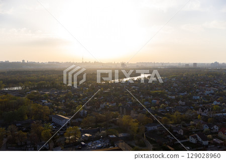 A Serene Sunrise Over a River View: Capturing the Beauty of Nature and Urban Life with Lush Greenery and a Glimpse of the City Skyline in the Distance A Serene Sunrise Over a River View: Capturing the Beauty of Nature and Urban Life with Lush Greenery and a Glimpse of the City Skyline in the Distance 129028960