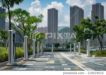 Multiple electric vehicle charging stations are lined up in a modern city setting, suggesting the increasing adoption of sustainable transportation 129029018