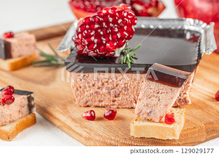 Gourmet liver pate topped with a glossy pomegranate jelly, served with bread and garnished with fresh pomegranate seeds and rosemary 129029177