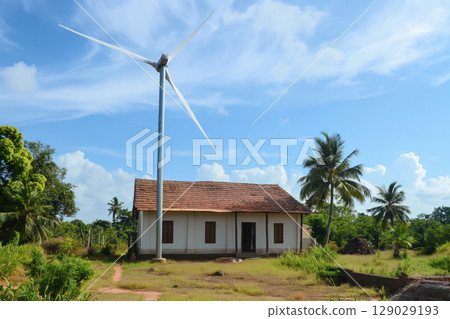 Single wind turbine is generating renewable energy for a rural house, showcasing the adoption of sustainable living practices in remote areas 129029193