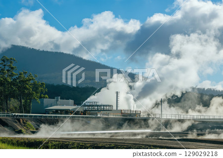 Geothermal power plant releasing plumes of steam into the atmosphere, showcasing renewable energy generation 129029218