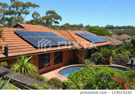Modern suburban houses using solar panels to produce renewable energy, with a swimming pool in the backyard 129029284