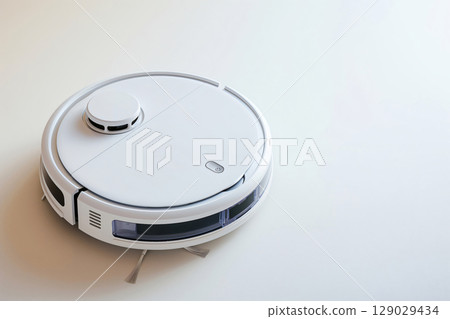White robot vacuum cleaner standing on a white floor, ready to clean a modern home 129029434