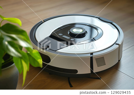Modern robotic vacuum cleaner standing on a wooden floor, ready to clean a modern home 129029435