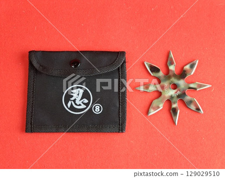 Star-shaped shuriken painted in military colors with a sheath on a red background. The inscription on the shuriken says Made in China. Star-shaped shuriken painted in military colors with a sheath on a red background. The inscription on the shuriken says Made in China. 129029510