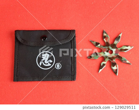 Star-shaped shuriken painted in military colors with a case on a red background. The inscription on the shuriken is Kohga Ninja. 129029511