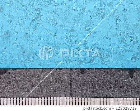 Aerial view of clear blue swimming pool with textured tiles and white border. water reflects light, creating serene and inviting atmosphere Aerial view of clear blue swimming pool with textured tiles and white border. water reflects light, creating serene and inviting atmosphere 129029712