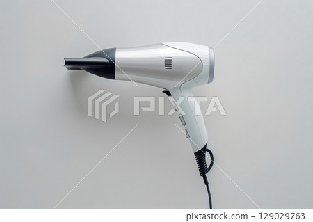 Modern hair dryer is lying on a white background, suggesting hairdressing and beauty concepts 129029763