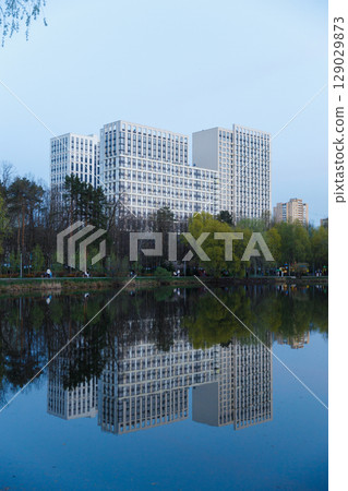 Modern Architectural Marvel Reflected in Tranquil Waters: A Stunning Evening Scene of Urban Development Nestled Amongst Nature's Beauty 129029873