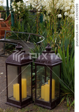 Charming Outdoor Setting Featuring Two Elegant Lanterns and Vibrant Greenery As a Backdrop for a Cozy, Inviting Atmosphere 129030099