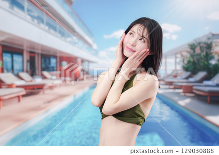 陽光明媚的度假勝地，一位身穿泳衣的女子正在臉上塗抹防曬霜 129030888