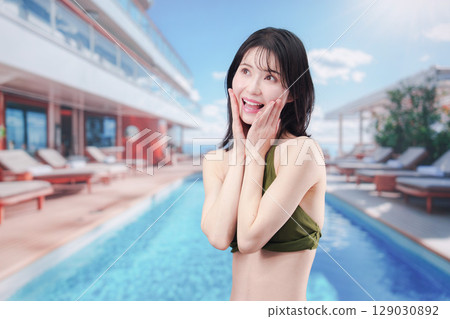 陽光明媚的度假勝地，一位身穿泳衣的女子正在臉上塗抹防曬霜 129030892