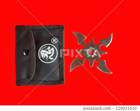 Throwing star shuriken, traditional Japanese ninja bladed weapon and black case on red background. Made in China inscription. 129031010