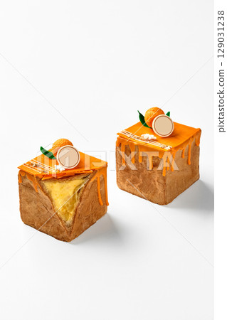 Two cubic mango cakes with orange icing dripping on white background Two cubic mango cakes with orange icing dripping on white background 129031238