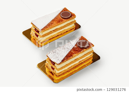 Two mille-feuille pastries with custard and chocolate resting on golden plates Two mille-feuille pastries with custard and chocolate resting on golden plates 129031276