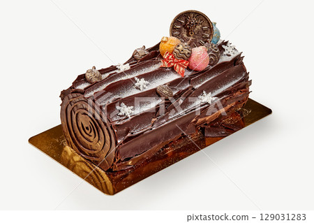Delicious chocolate yule log cake decorated with christmas ornaments and icing sugar 129031283