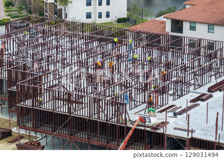 Workers assembling metal frame building at industrial construction site. Housing development in America. Real estate market in the USA 129031494