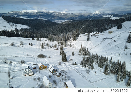 Winter landscape with small rural houses in remote settlement between snow covered forest in cold mountains 129031502