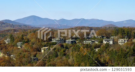 View from above of expensive residential houses high on hill top between yellow fall trees in suburban area in North Carolina. American dream homes as example of real estate development in US suburbs View from above of expensive residential houses high on hill top between yellow fall trees in suburban area in North Carolina. American dream homes as example of real estate development in US suburbs 129031593