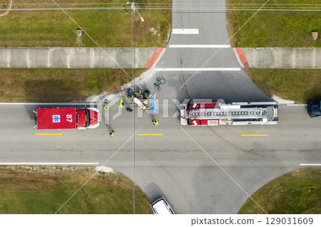 Victim of traffic accident on paramedics stretcher on American street. First responders and emergency medical technicians helping cyclist at car crash on road in USA 129031609