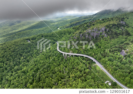 Viaduct bridge on winding parkway road in mountain forest with green canopies in summertime. Driving in North Carolina wild woods nature in summer 129031617