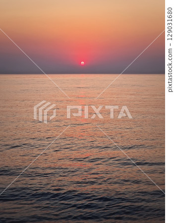 Captivating sunrise over the calm sea. Peaceful seascape at dawn with soft gradients of orange and pink on the sky reflecting on the water 129031680