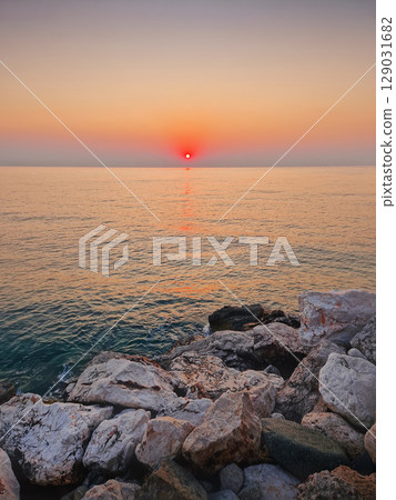 Captivating sunrise over the calm sea. Peaceful seascape at dawn with soft gradients of orange and pink on the sky reflecting on the water 129031682