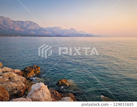 Kemer coastline view with majestic Taurus mountains towering over the calm sea in the morning at sunrise. Turkey mediterranean sea coast scenery Kemer coastline view with majestic Taurus mountains towering over the calm sea in the morning at sunrise. Turkey mediterranean sea coast scenery 129031685