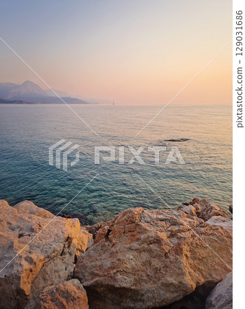 Kemer coastline view with majestic Taurus mountains towering over the calm sea in the morning at sunrise. Turkey mediterranean sea coast scenery 129031686