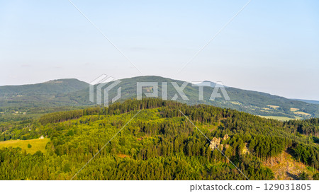 Witness the breathtaking sunset over Jested Ridge as viewed from the Popov Cliffs in the Lusatian Mountains, featuring lush green forests and striking sandstone formations during evening. 129031805