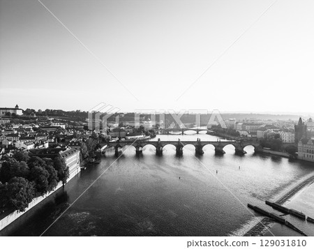 This captivating aerial view showcases the historic Charles Bridge in Prague at sunrise. The tranquil Vltava River reflects the soft morning light, highlighting the city's charm. This captivating aerial view showcases the historic Charles Bridge in Prague at sunrise. The tranquil Vltava River reflects the soft morning light, highlighting the city's charm. 129031810