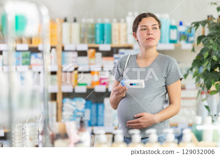Pregnant woman choosing an ointment at the pharmacy Pregnant woman choosing an ointment at the pharmacy 129032006
