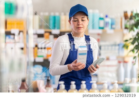 In sales area of pharmacy, builder woman examines packaging of cream In sales area of pharmacy, builder woman examines packaging of cream 129032019