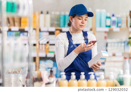 Young woman worker scanning qr code of cream 129032032