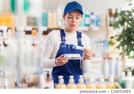 In sales area of pharmacy, builder woman examines packaging of gel for burns In sales area of pharmacy, builder woman examines packaging of gel for burns 129032065