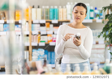 Asian woman choosing syrup in pharmacy Asian woman choosing syrup in pharmacy 129032071