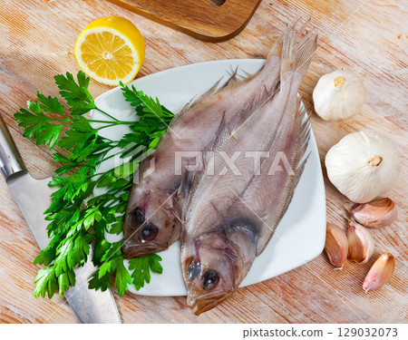 Two raw megrims on wooden table with condiments 129032073