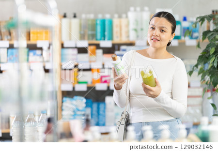 Young female customer choosing shampoo in local drugstore 129032146