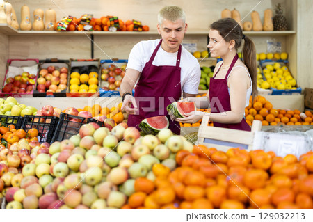 Two vendors lay out fruits and watermelons in a supermarket Two vendors lay out fruits and watermelons in a supermarket 129032213