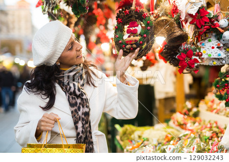 Latin American woman chooses Christmas souvenirs and toys 129032243