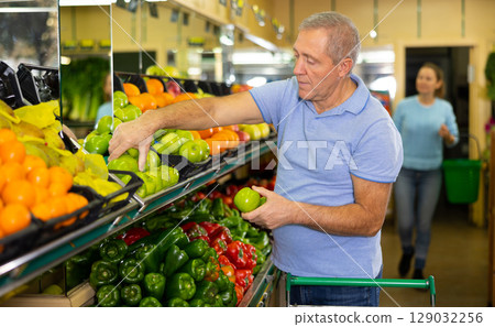 Elderly man purchaser buying fresh apples in grocery store Elderly man purchaser buying fresh apples in grocery store 129032256