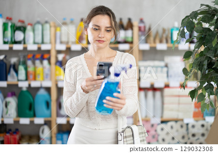 Young woman scanning qr code for cleaning spray Young woman scanning qr code for cleaning spray 129032308