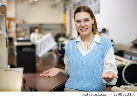 Friendly print shop employee invites customer to come inside 129032310