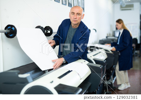 Man using printer while working in print shop 129032381