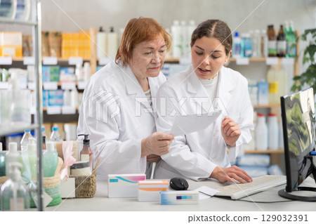 Two female pharmacists checking prescription on computer Two female pharmacists checking prescription on computer 129032391