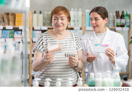 mature woman chooses paracetamol and consults a pharmacist 129032438