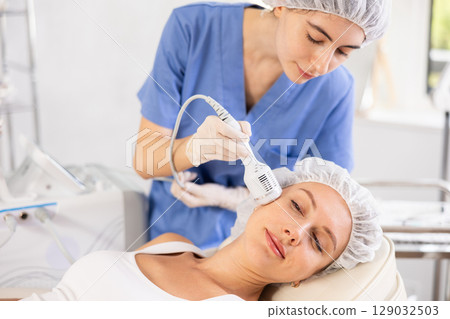 Young woman cosmetologist doing whitening procedure to young woman 129032503